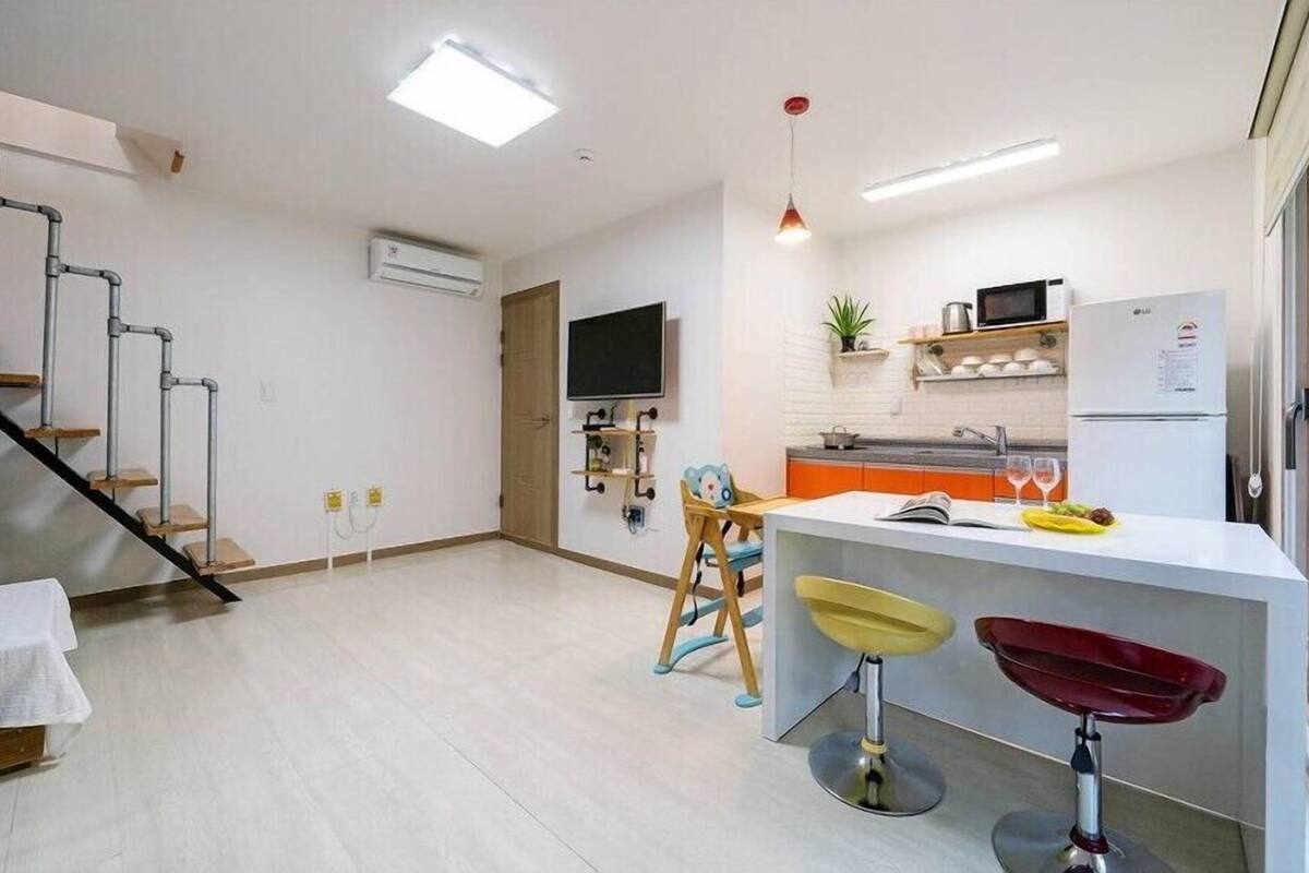 Una cocina moderna con microondas incorporado, un refrigerador y una zona de comedor con dos taburetes.