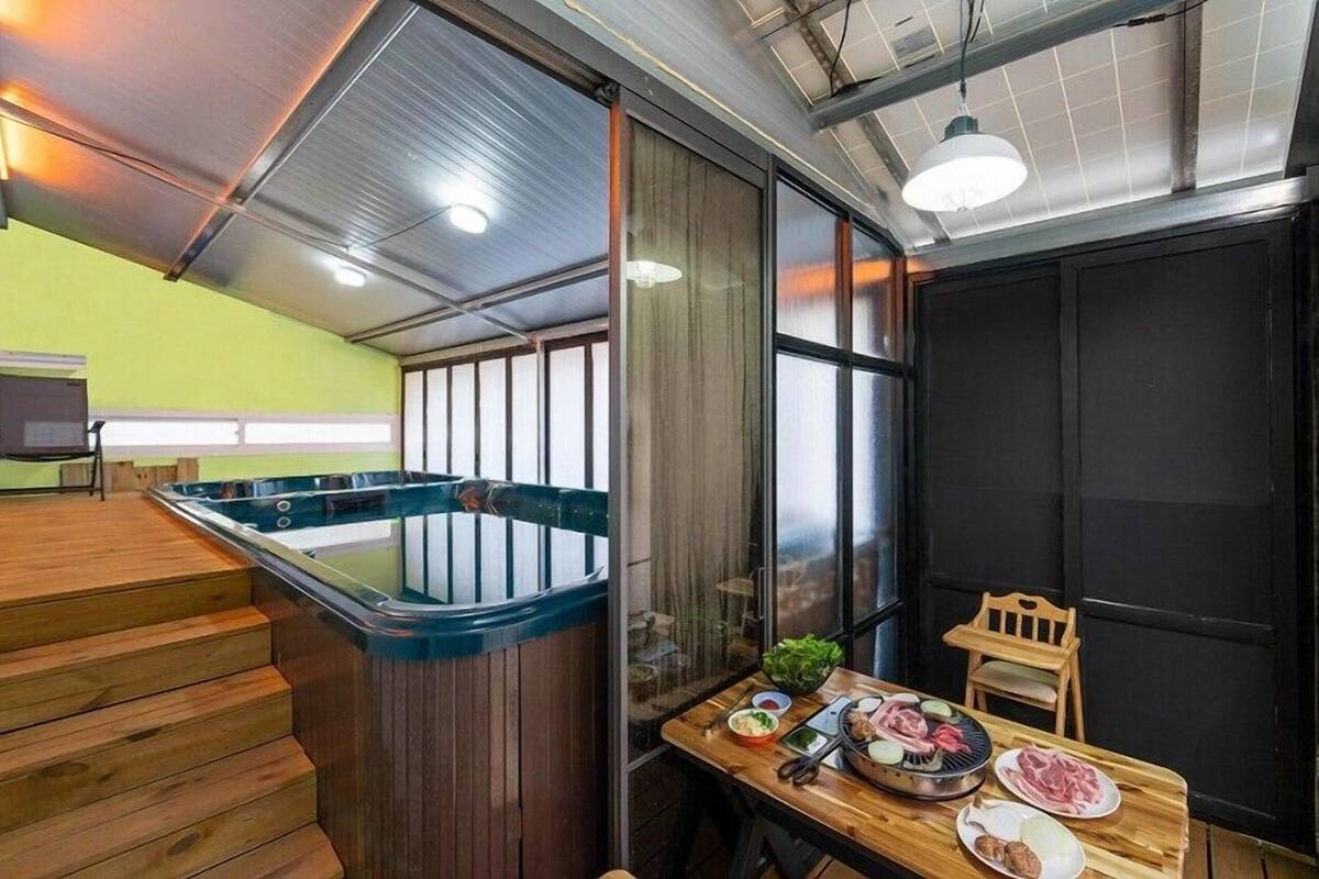 Una cocina moderna con una mesa de madera lista para comer, un jacuzzi y una escalera que lleva a un nivel superior.