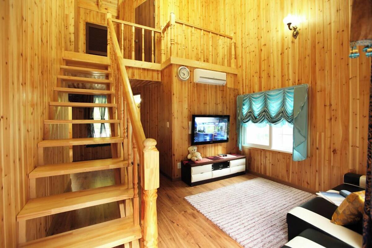 A wooden interior with a staircase, a television, and a sofa.