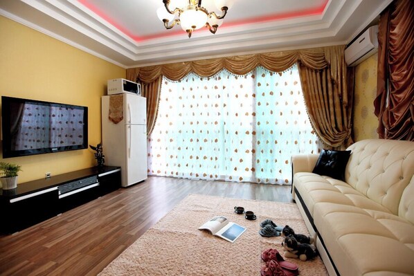 A living room with a flat-screen TV, a sofa, a coffee table, and a rug.