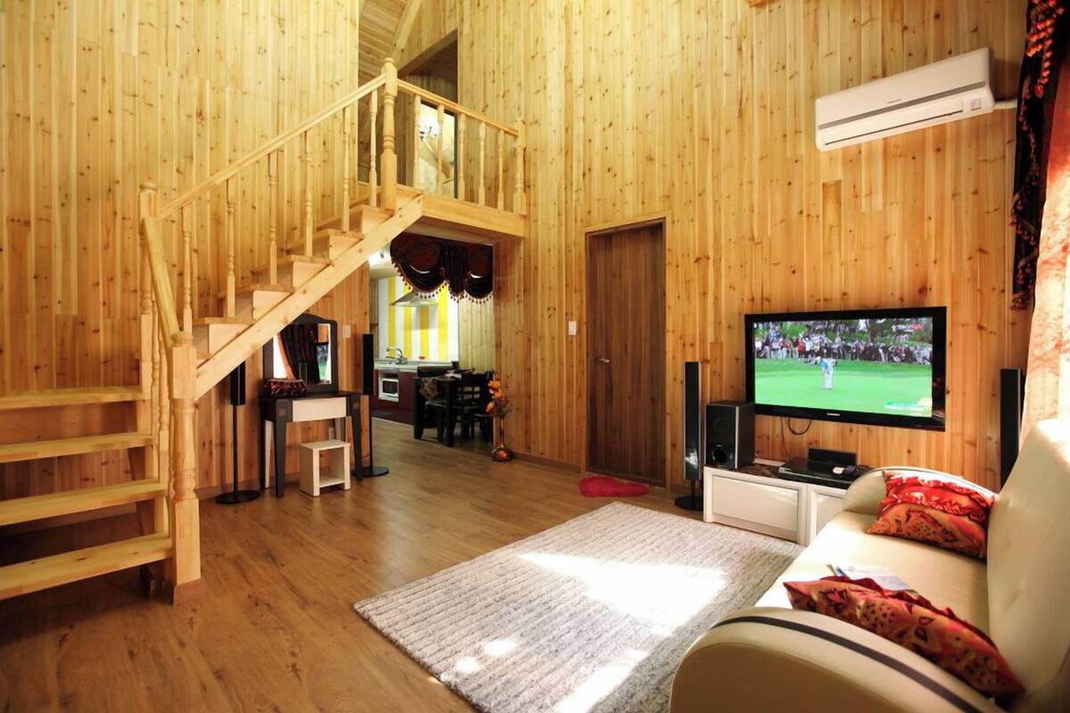 A wooden interior with a staircase, a TV, and a sofa.
