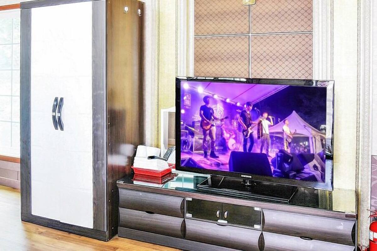 A living room with a TV on a stand, a white cabinet, and a door.
