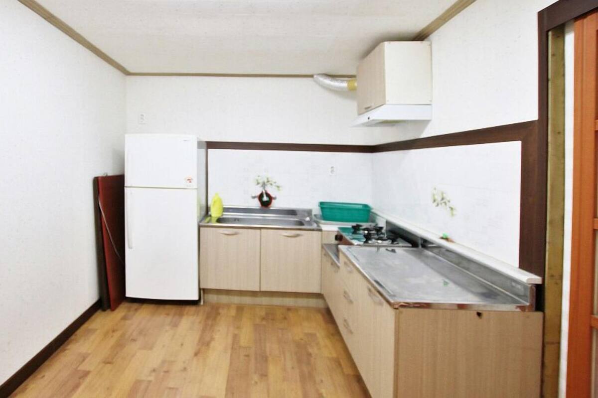 A compact kitchen with wooden cabinets, a sink, and a refrigerator.