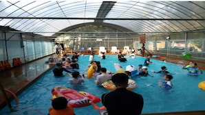 An indoor swimming pool with a glass ceiling, surrounded by chairs and life vests. - Mirim Pension (Incheon)