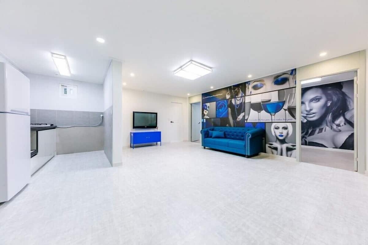 A modern living room with a blue sofa, a flat-screen TV, and a wall with abstract art.