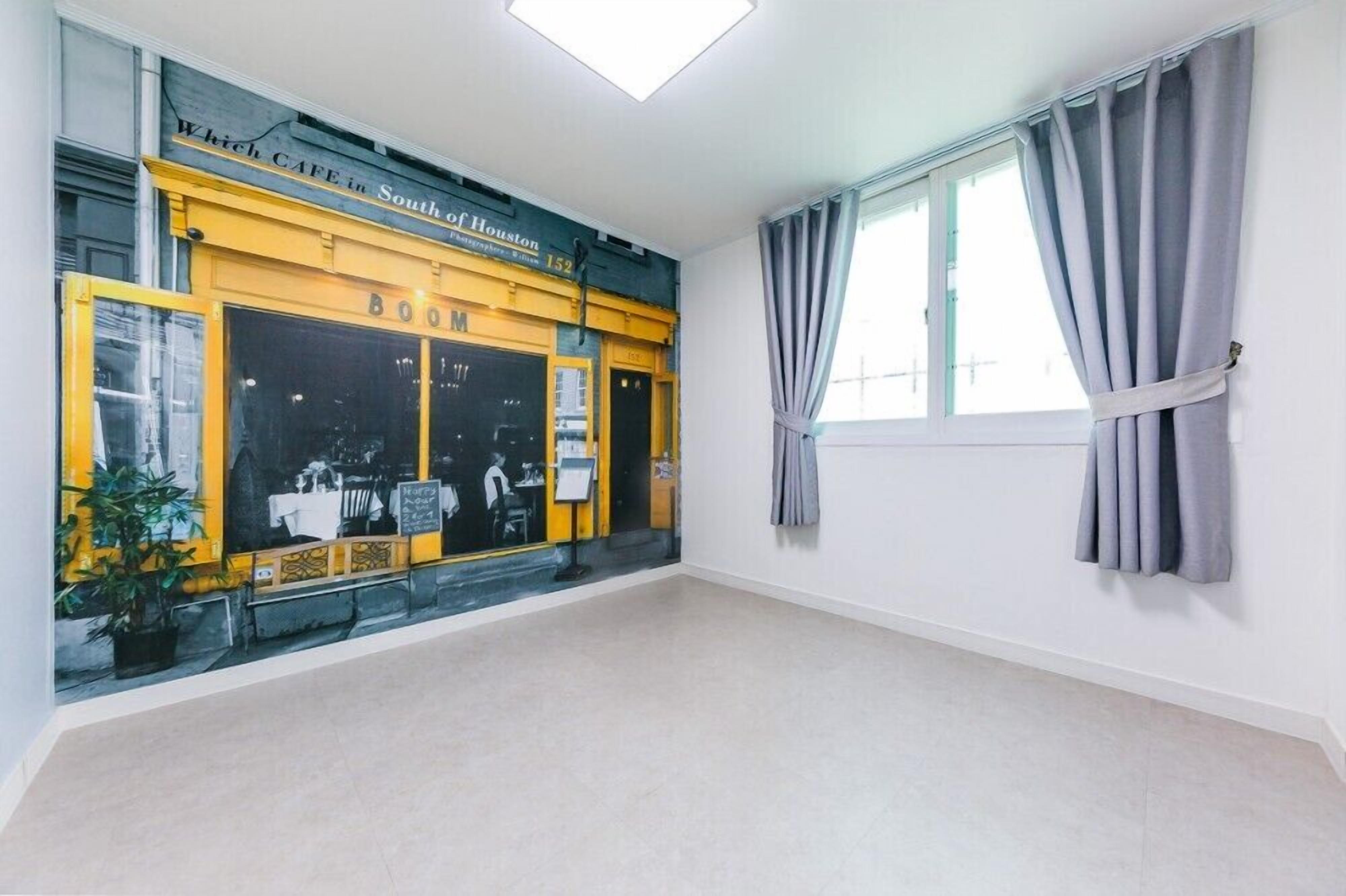 A room with a large window, a door, and a wall with a mural.