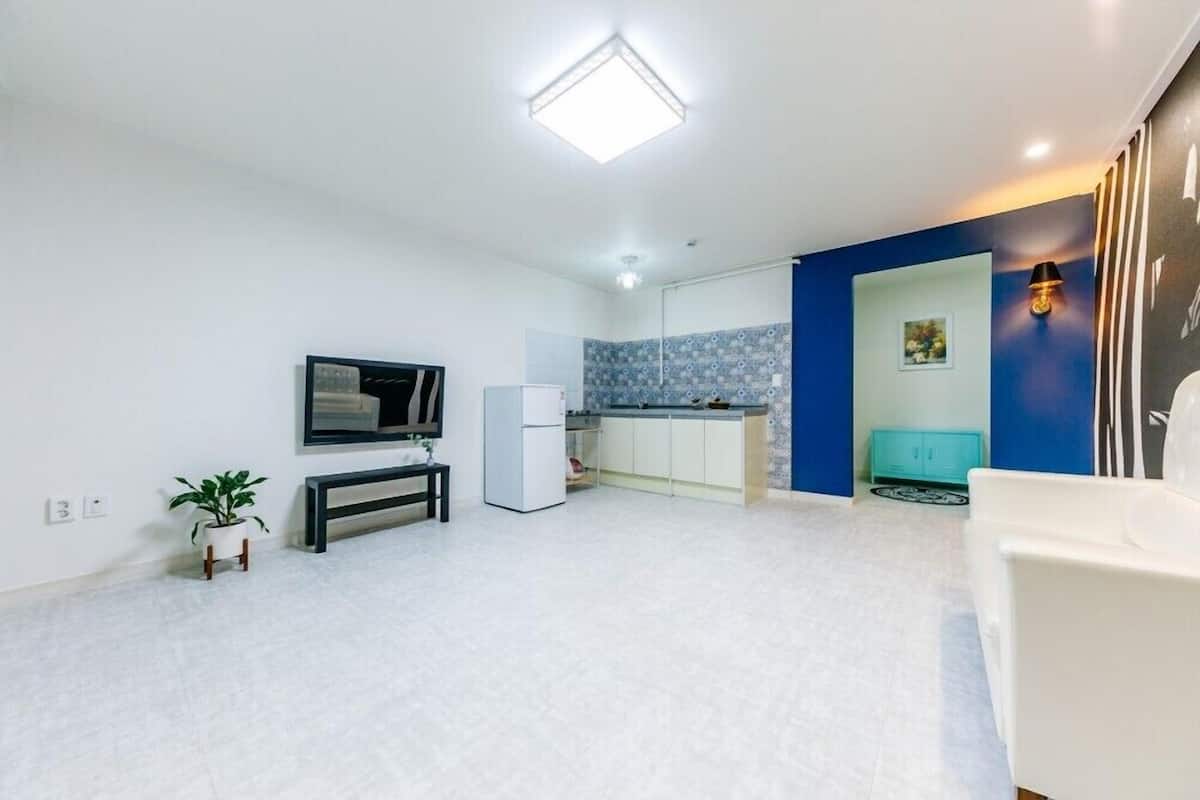 A modern living room with a flat-screen TV, a small table, a plant, and a sofa.