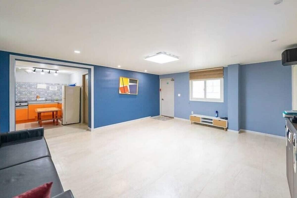 A spacious living area with a sofa, a television, and a kitchen in the background.