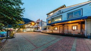Un hotel con un patio empedrado, una zona de estar al aire libre techada y una montaña al fondo.