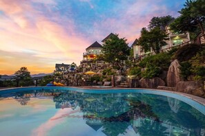 Um resort com piscina, vista para as montanhas e um pôr do sol.