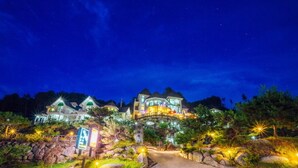 A large, multi-story hotel with a prominent entrance and a landscaped driveway. - Wellbeing log Pension (Gapyeong)