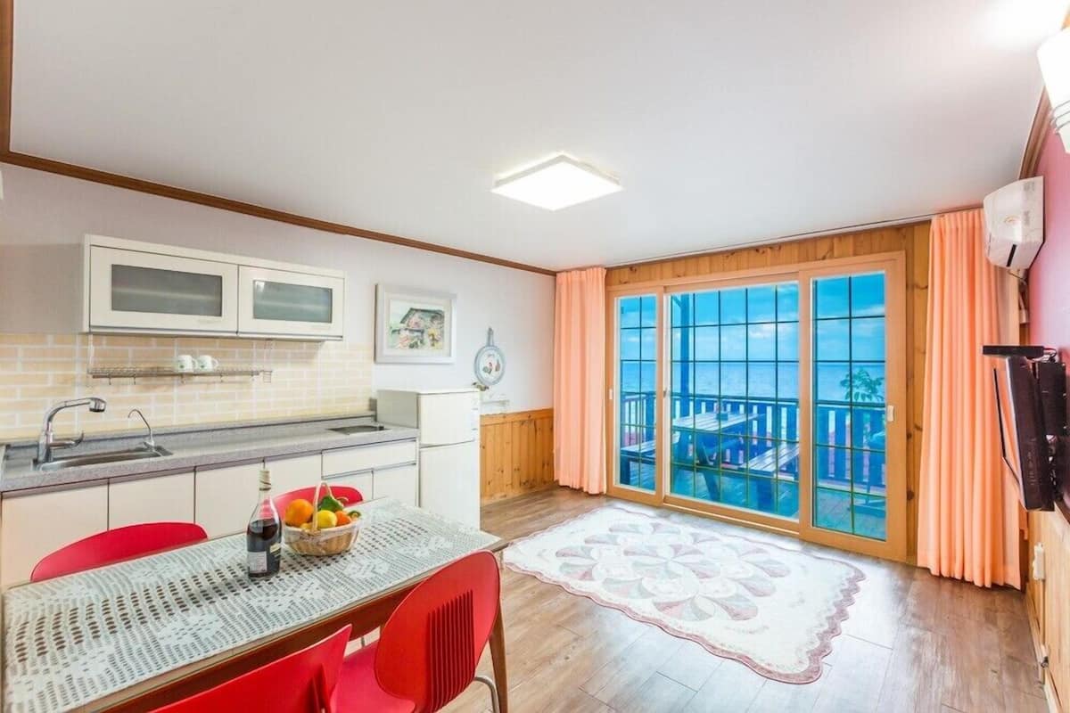 A kitchen with a dining table, chairs, and a view of a balcony.