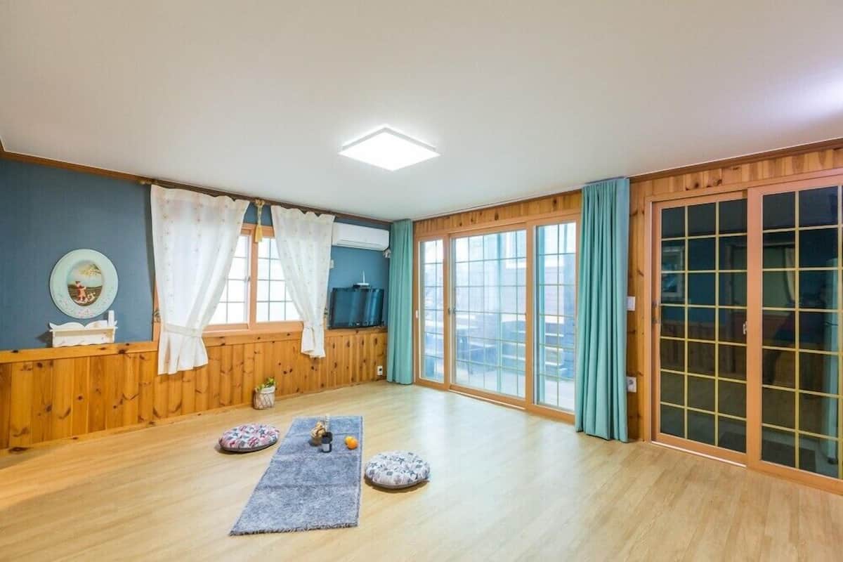 A spacious room with wooden flooring, a large sliding glass door, and a ceiling light.