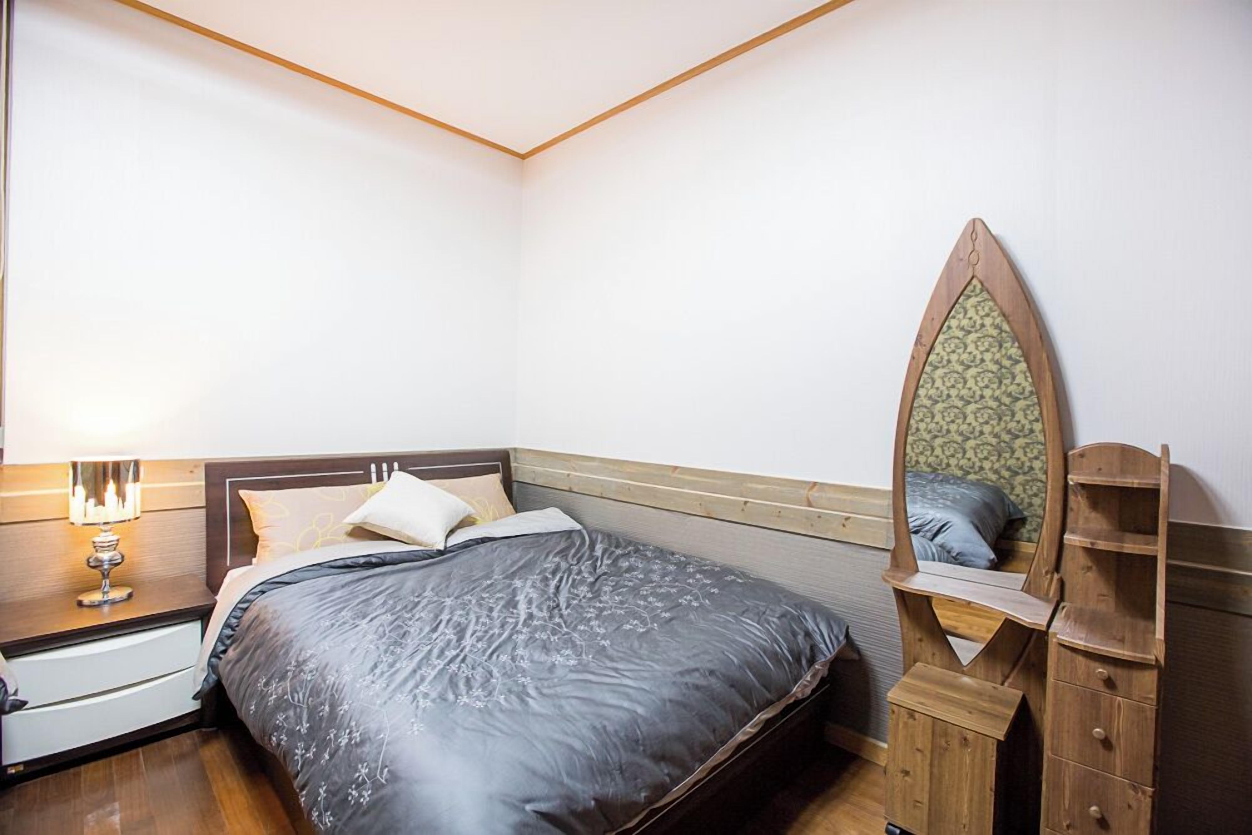 Un dormitorio con cama, mesita de noche, cómoda y espejo.