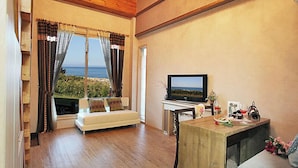 Una sala de estar acogedora con un sofá, un televisor y una mesa de madera con vista al mar.