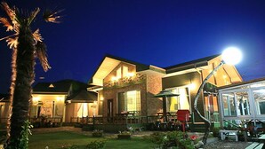 Un edificio bien iluminado con un patio, mesas al aire libre y un pequeño jardín.