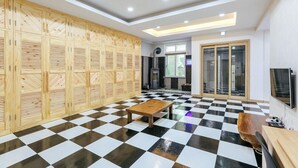 A modern room with a checkered floor, wooden lockers, a fireplace, and a TV. - Sun and moon pension (Ansan)