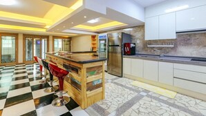 A modern kitchen with a bar area, a refrigerator, and a coffee machine. - Sun and moon pension (Ansan)