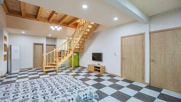 Een slaapkamer met een geruite vloer, een bed, een houten trap, een televisie en een garderobe.