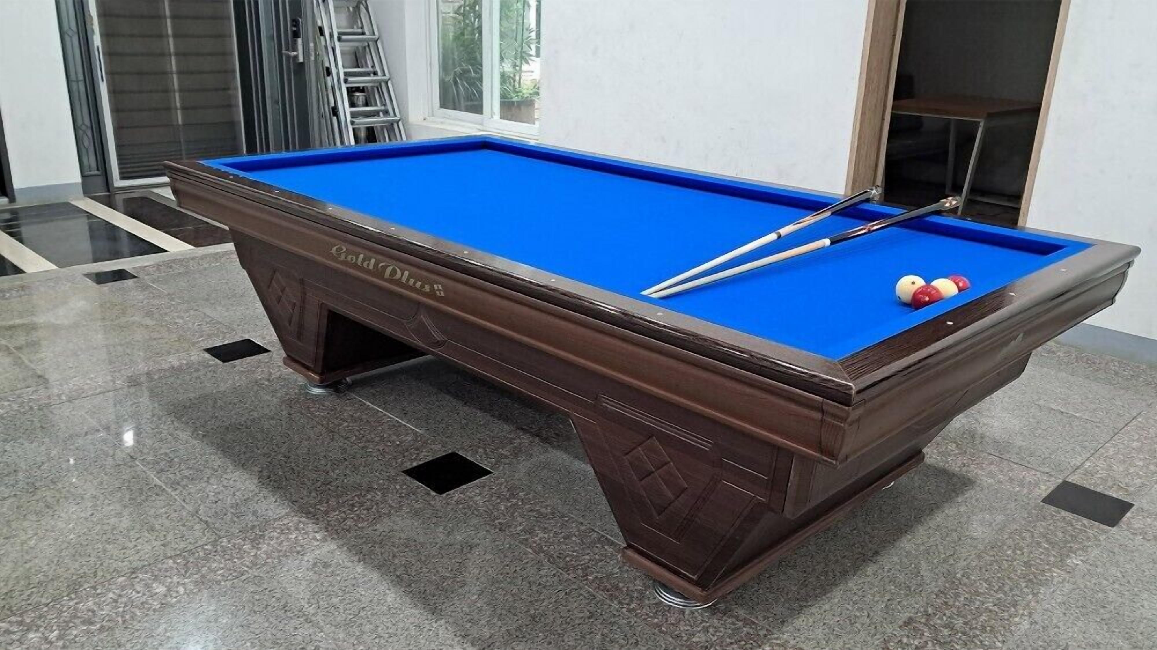 A pool table with a blue felt surface, two pool cues, and three billiard balls.
