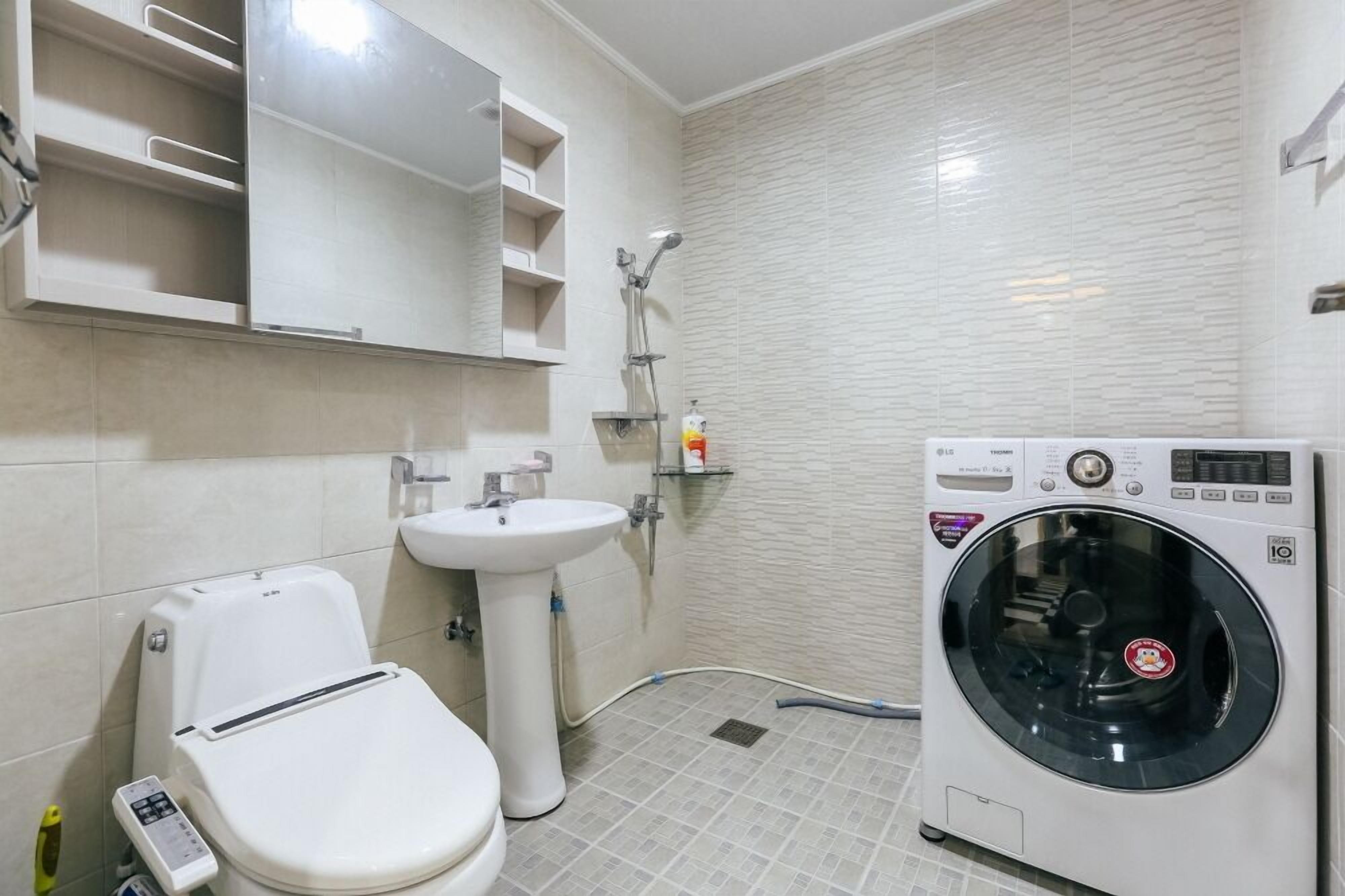 A compact bathroom with a toilet, sink, and built-in washing machine.