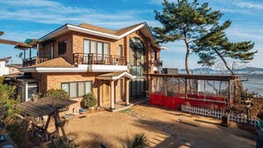 Une maison à deux  étages dotée d’un balcon, d’une terrasse couverte et offrant une vue sur l’eau.
