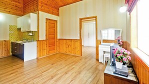 Una habitación amplia con suelo de madera, kitchenette, zona de comedor y escritorio.