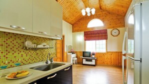 Una cocina con techo de madera, un lavamanos y una zona de comedor con televisor.