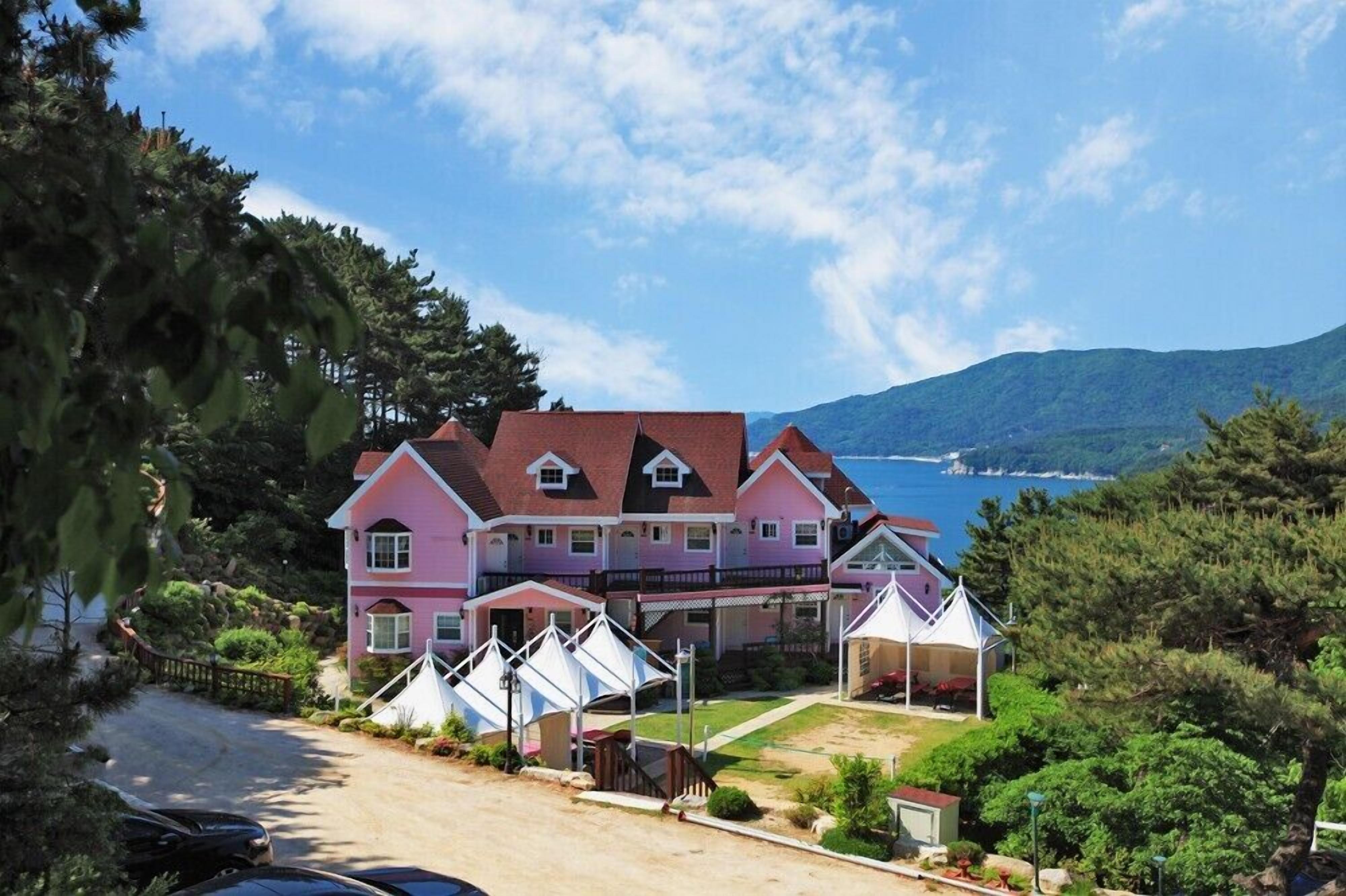 Una hilera de casas rosadas con vista al mar y a las montañas.