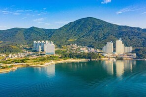 A coastal cityscape with modern high-rise buildings, a bay, and a mountain backdrop. - Aroma Tree Pension (Geoje)