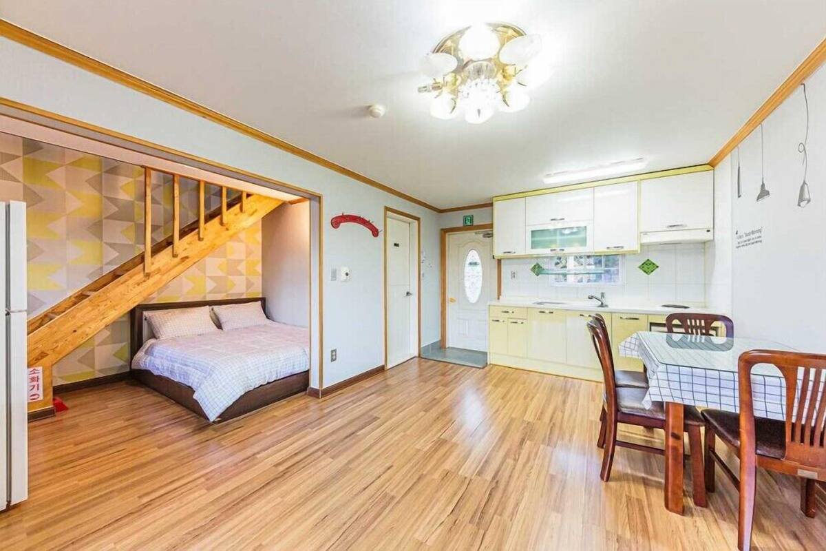 A compact apartment with a loft bedroom, a small kitchen, and a dining area.