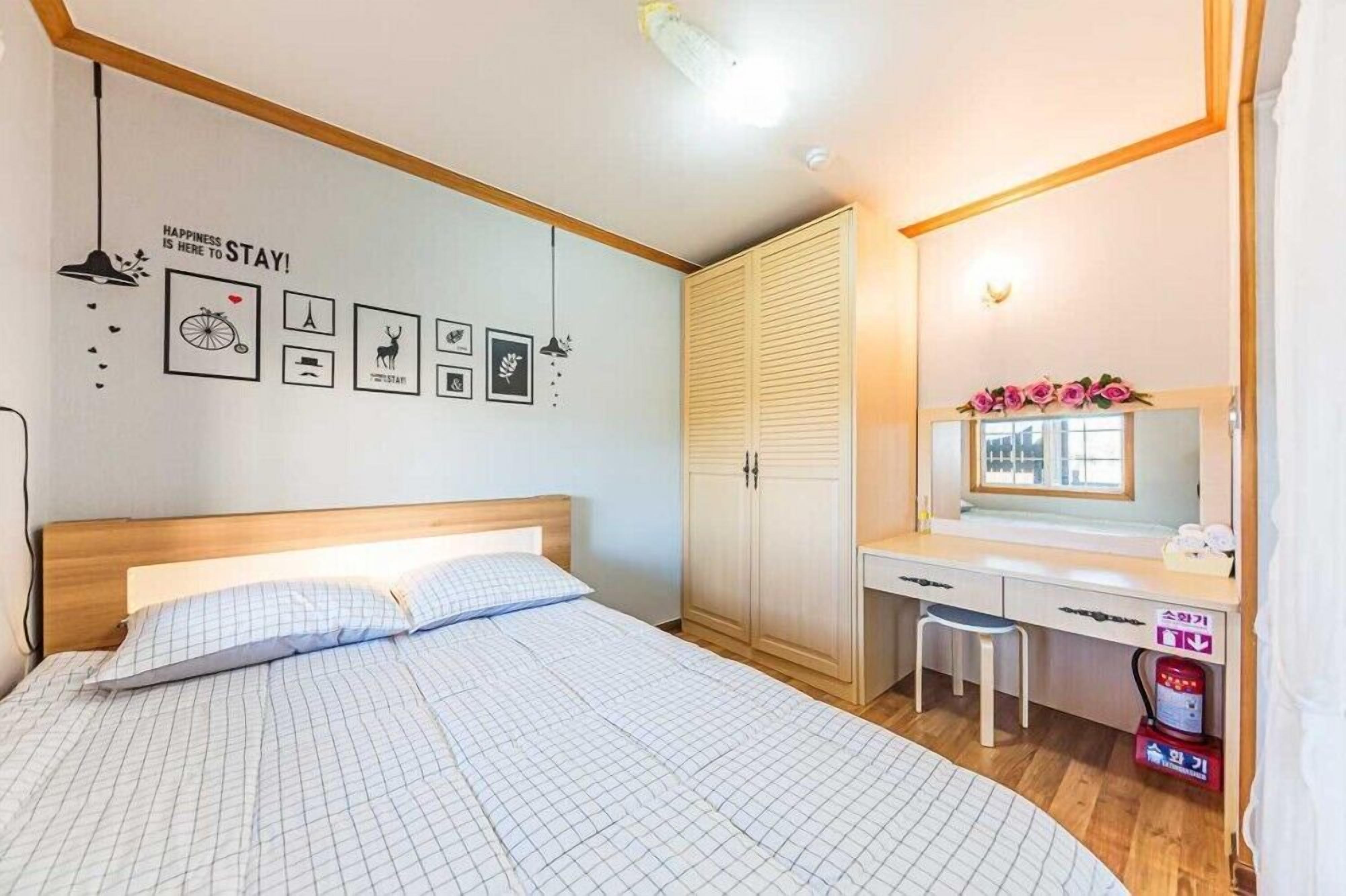 Une chambre à coucher avec un lit, un bureau, un miroir et une armoire.