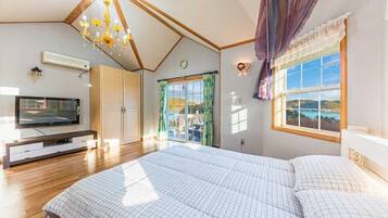Un dormitorio con una cama grande, televisión, armario y ventana con vistas.