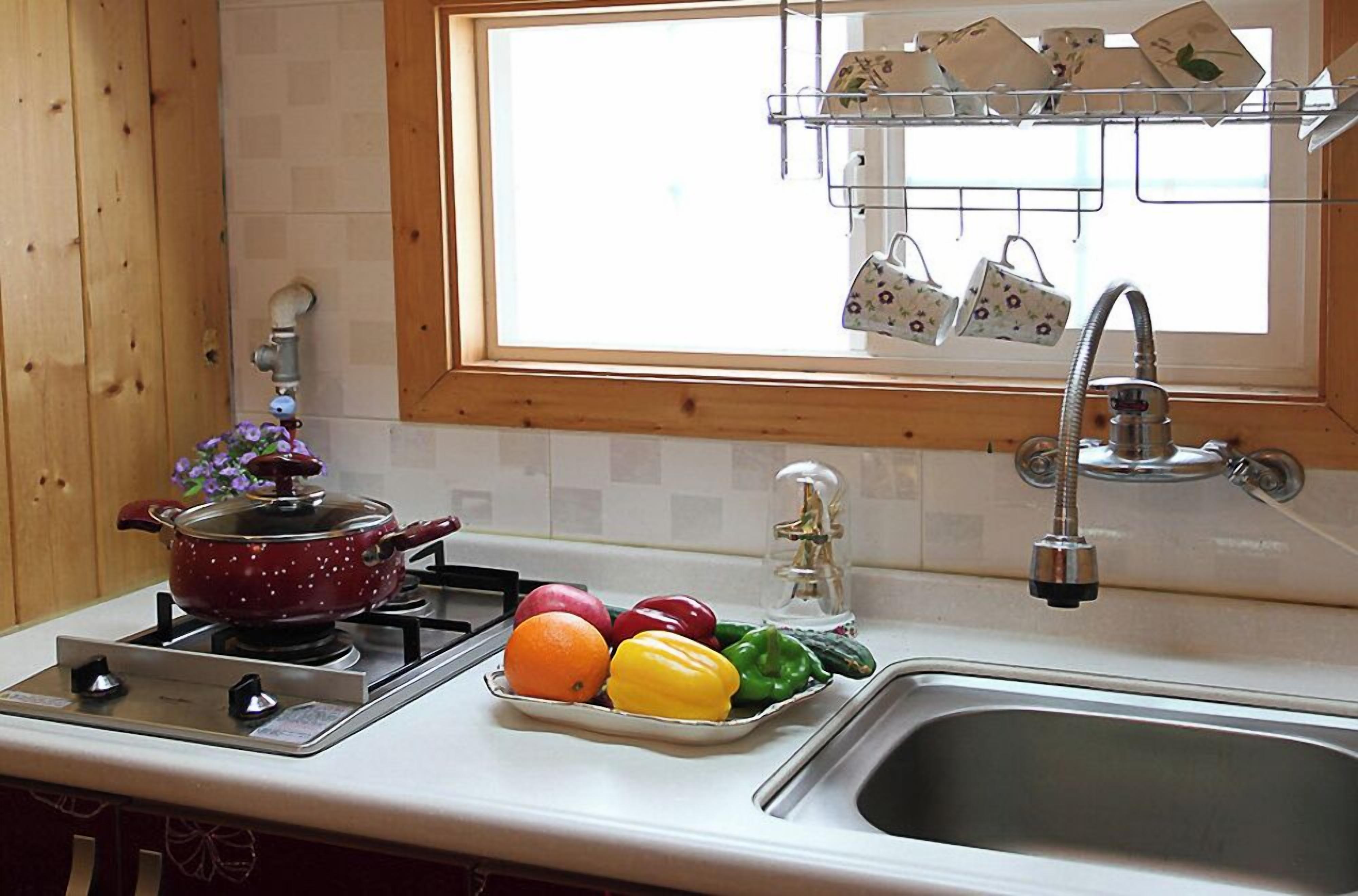 Una cocina con estufa, lavamanos y ventana.