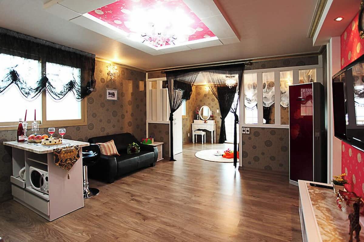 Una sala de estar moderna con un sofá, una mesita con bebidas, una lavadora y un televisor.