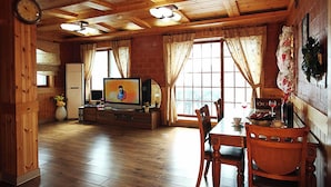 Un interior de madera con una mesa de comedor, sillas, un televisor y un reloj.