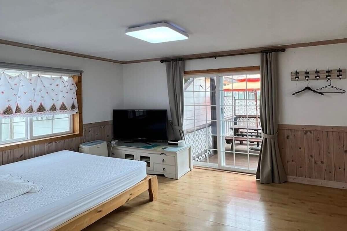 Un dormitorio con cama, televisor, escritorio y balcón con vistas.
