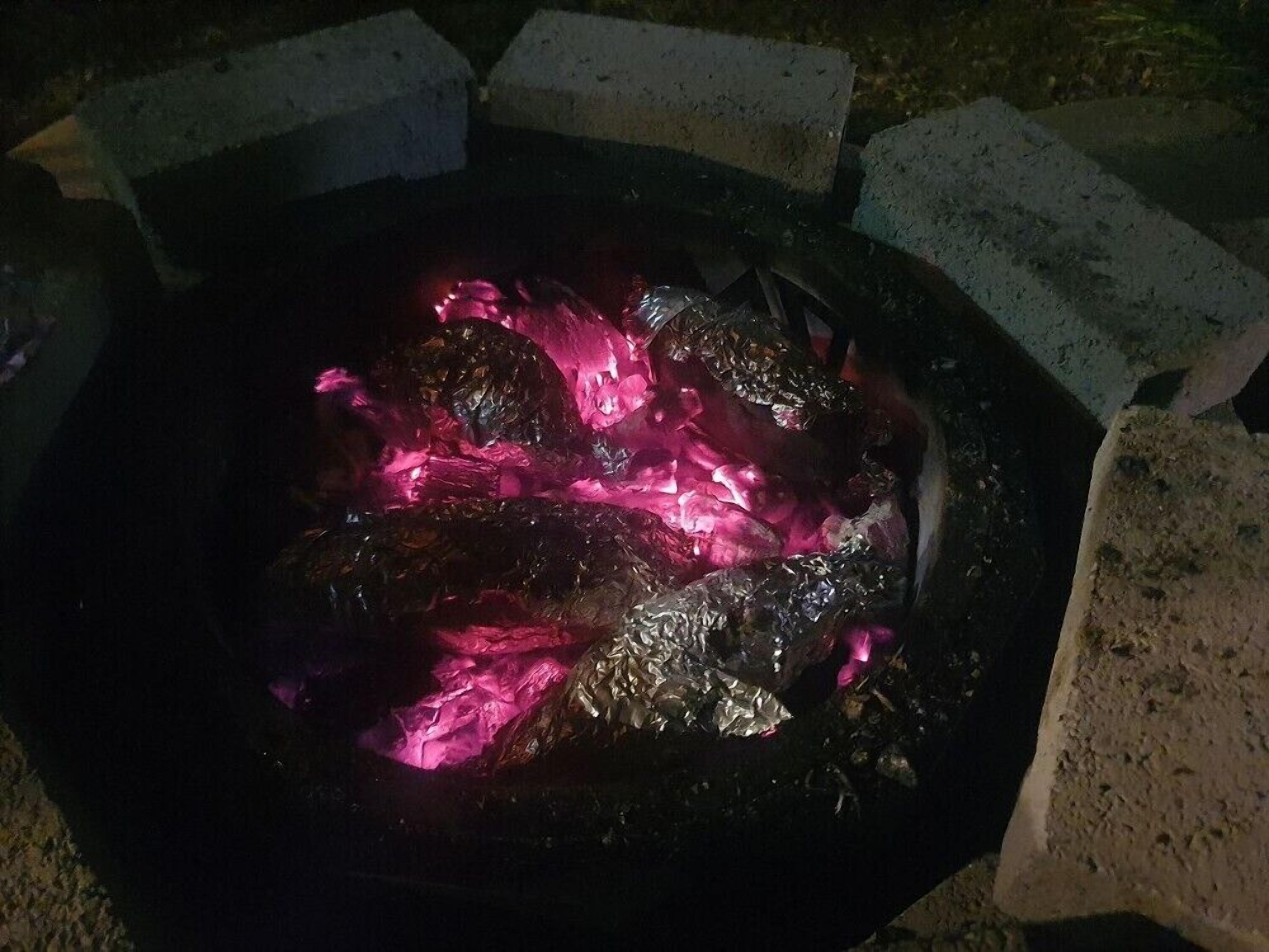 A fire pit with glowing embers, surrounded by concrete blocks.