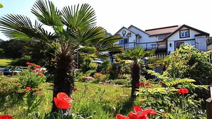 A residential area with a house featuring a balcony and a garden with various plants and flowers. - Haemaru pension (Geoje)