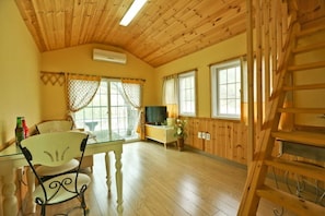 A cozy room with wooden walls and ceiling, a dining table with chairs, a TV, and a ladder. - Asteria Pension (Gapyeong)