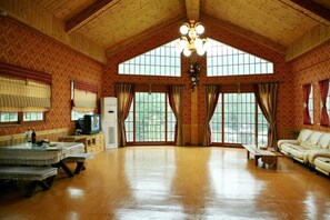 Un salon spacieux doté de parquets en bois, de grandes fenêtres, d’un lustre et d’un canapé.