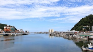 A harbor with boats docked, buildings along the waterfront, and a clear sky. - Badasae Pension (Yeongdeok)