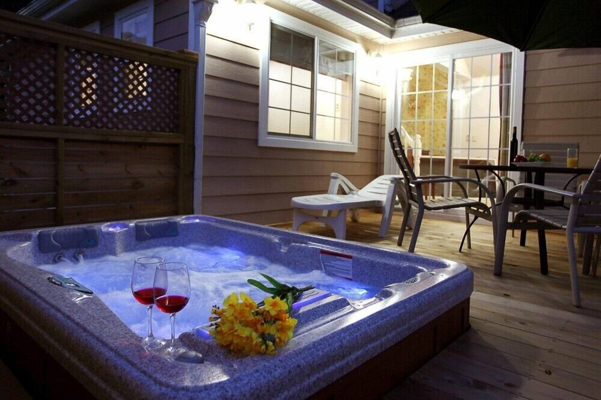 Un jacuzzi con dos copas de vino tinto y un ramillete de flores.