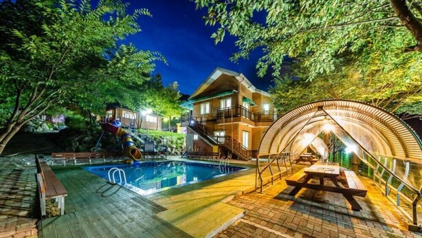 A pool area with a wooden deck, a picnic table, and a covered seating area. - Utbeodeong Pension (Chuncheon)