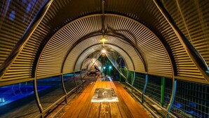 A covered walkway with a wooden bench in the center, metal railings, and a light fixture above. - Utbeodeong Pension (Chuncheon)