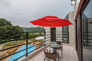A balcony with a pool, a red umbrella, and a view of the mountains. - Asamo poolvilla (Gapyeong)