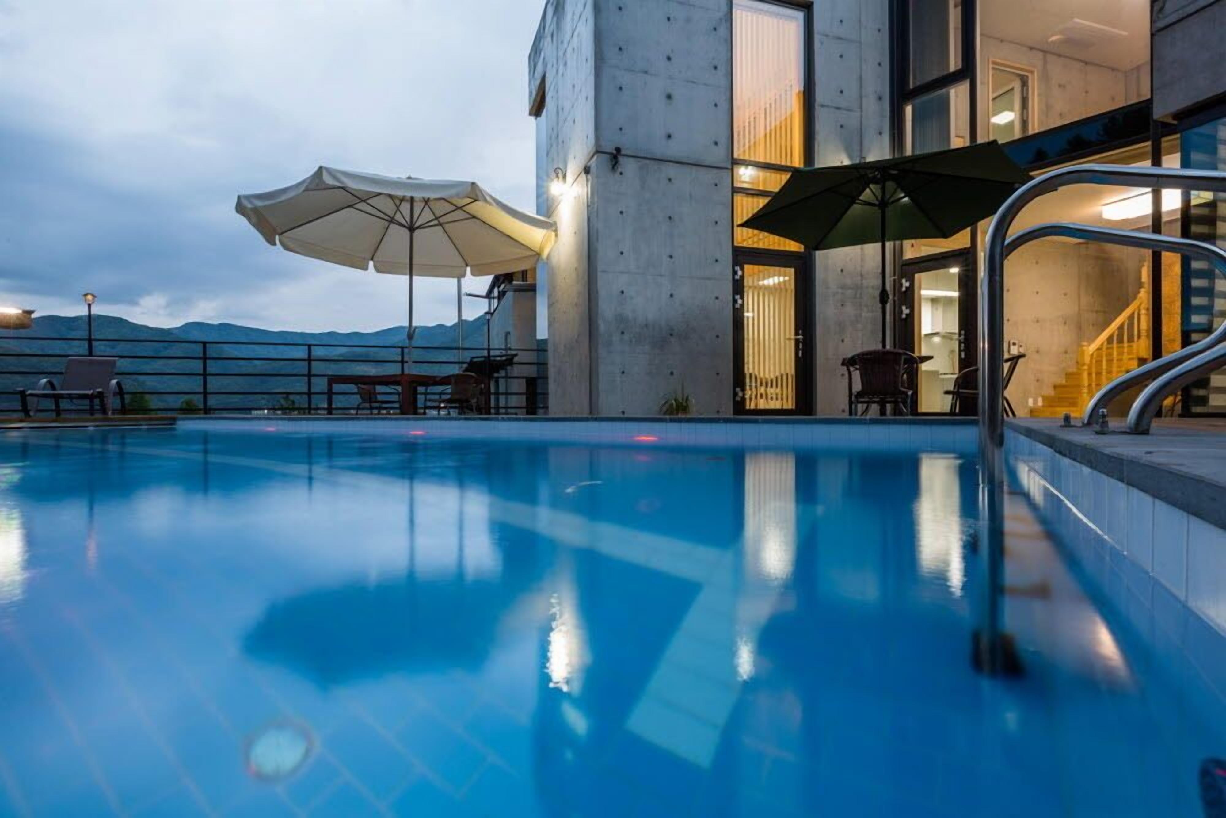 A swimming pool with umbrellas, a staircase, and a view of mountains.
