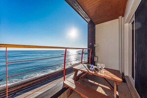 A balcony with a wooden table, a glass of water, and a wine glass. - Sea Island Pension (Yeongdeok)