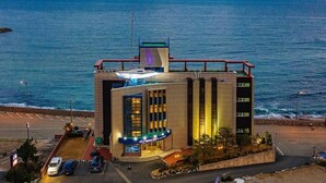 Un hôtel au design moderne, caractérisé par une façade incurvée, une terrasse sur le toit et une vue sur l’océan.