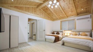 Un dormitorio con dos camas, un armario y un techo con vigas de madera e iluminación empotrada.
